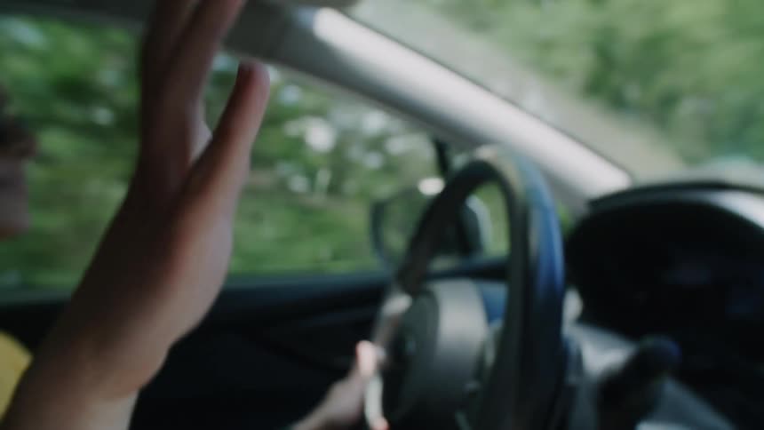 A woman dances while driving in her car