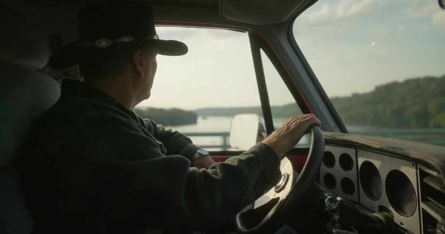 A man is driving a truck across a bridge over water