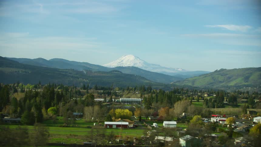 A small town sits below snow capped mountains
