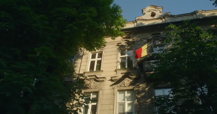 The belgian flag waves in the wind on a city building