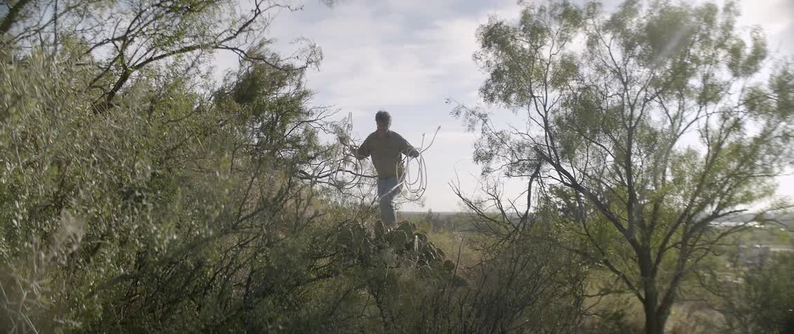 Man walks through a rural area with objects in hand
