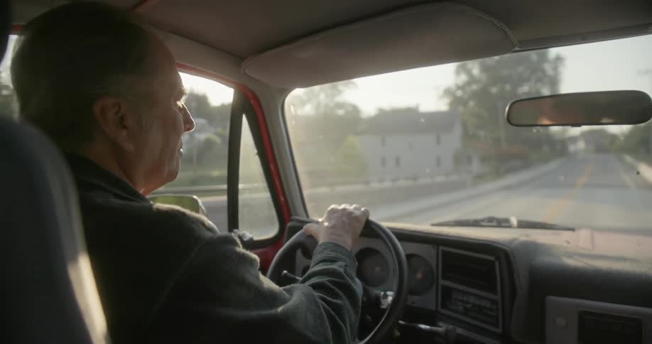 A man drives his truck through a neighborhood