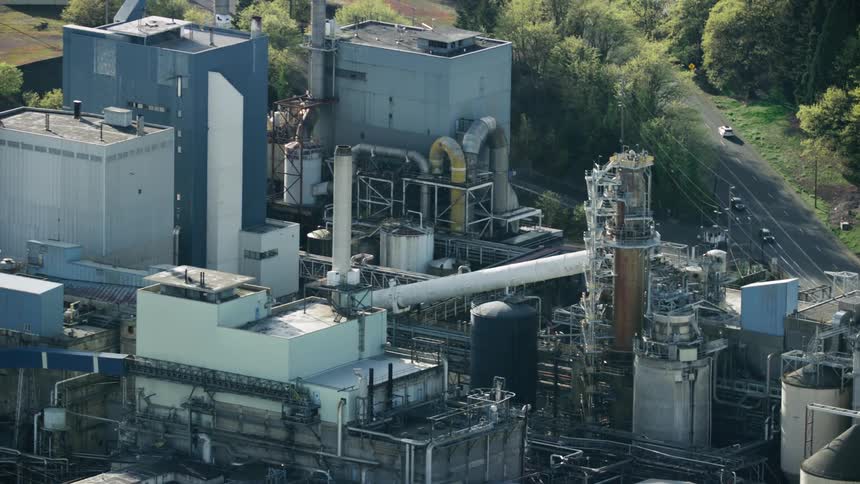 Traffic passes by a large paper mill factory as seen from the air in late spring season