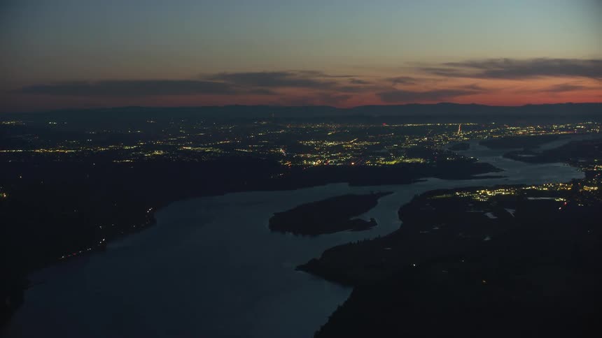 Planes are taking off and landing at an airport in a city on a river in this aerial time lapse of Portland Oregon