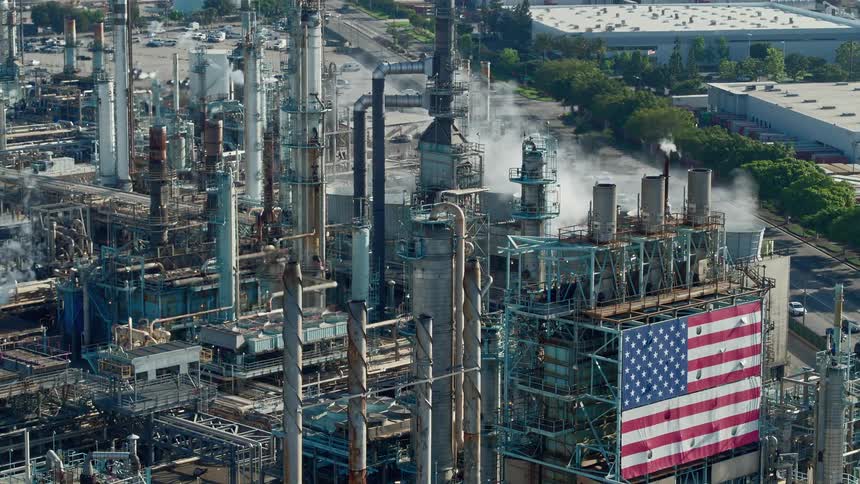 Traffic passes by factory decorated by large torn american flag