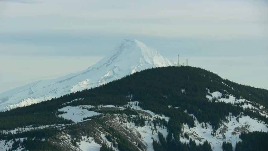 Cell phone towers dominate the skyline in this extremely scenic aerial as the cell towers pass in front of a massive mountain in winter