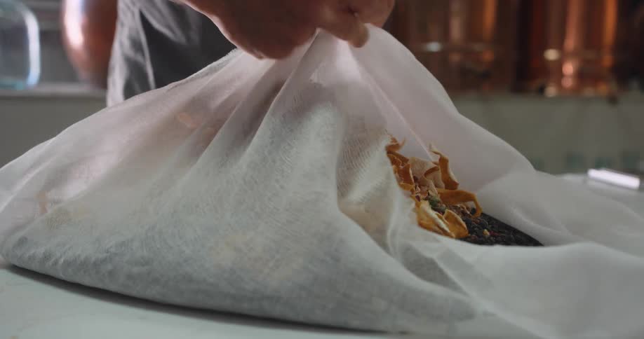 A man ties dried flowers and fruit in a large cheesecloth