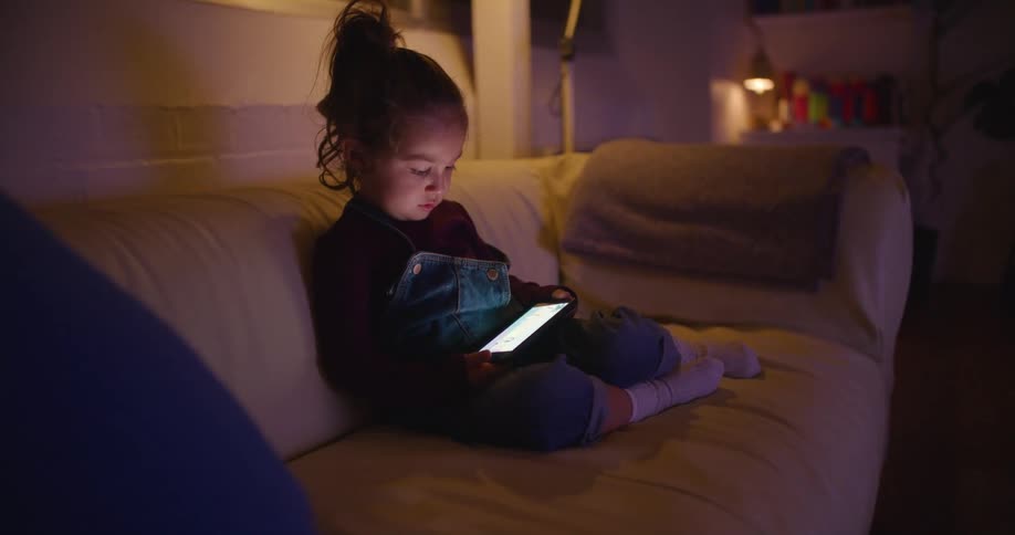A child is looking at a phone on the couch