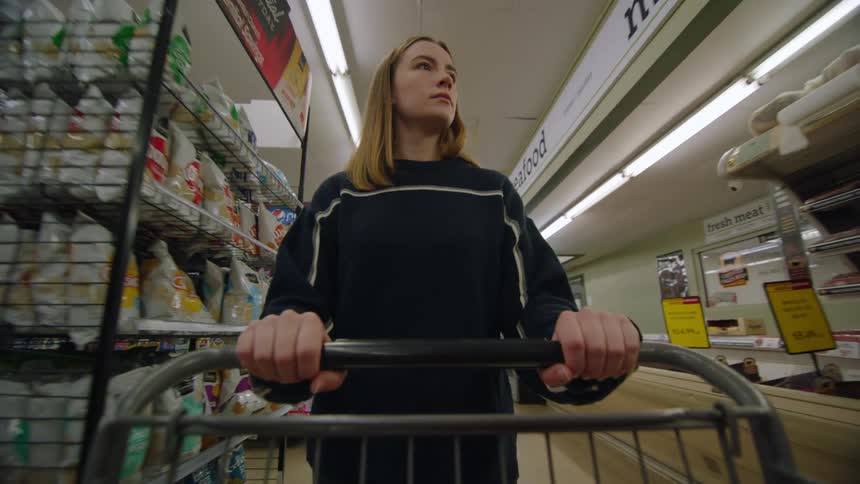 Woman walks through grocery store pushing a grocery cart