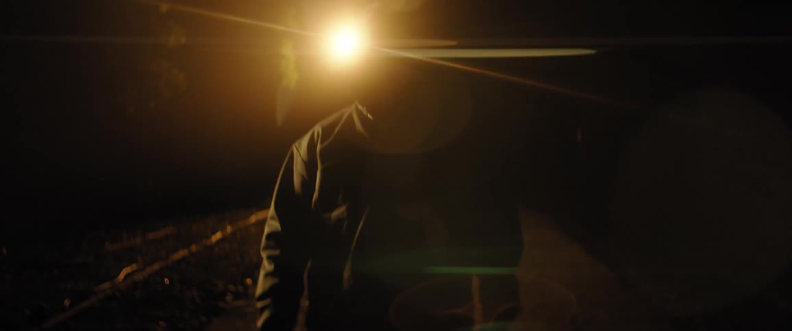 A man in a coat walks in the dark