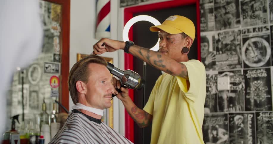 A barber cuts a mans hair in his salon