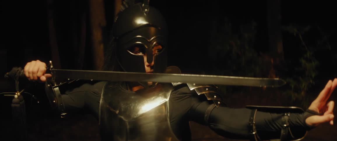 A woman in armor holds a sword with her other hand extended infront of her