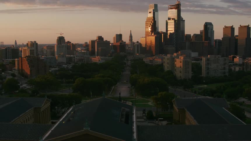 The sun is rising and reflecting off the windows of a skyscraper in a city