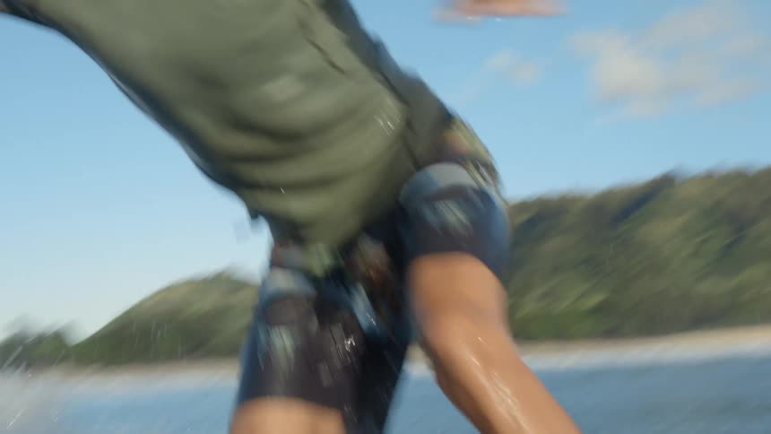 Man surfs in the ocean while another male goes under the water