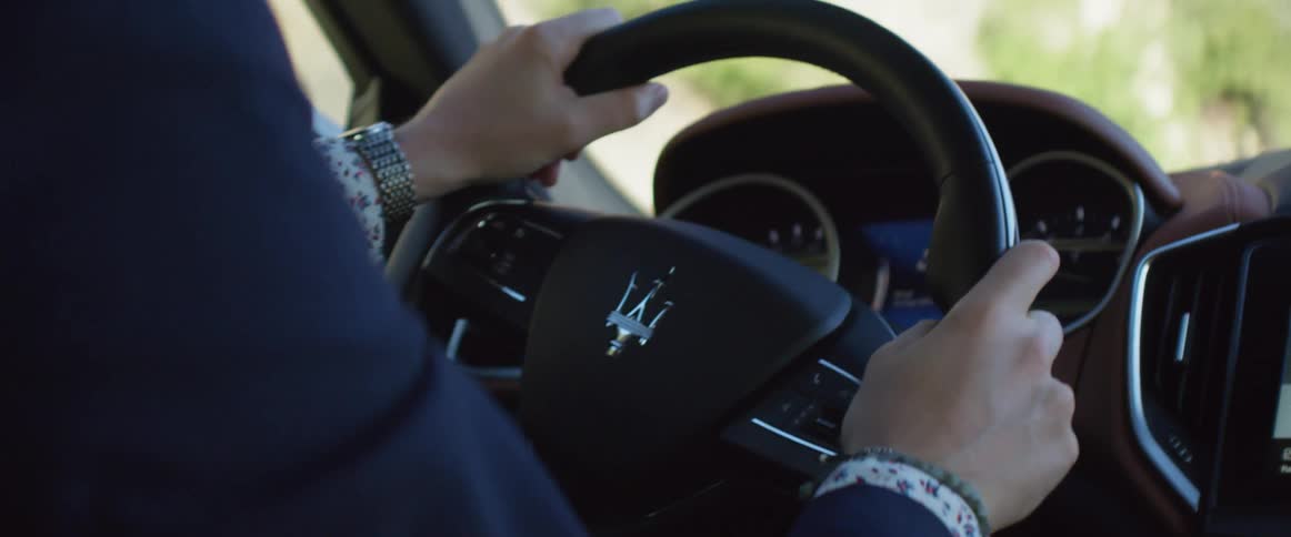 A man drives with both hands on his maserati steering wheel