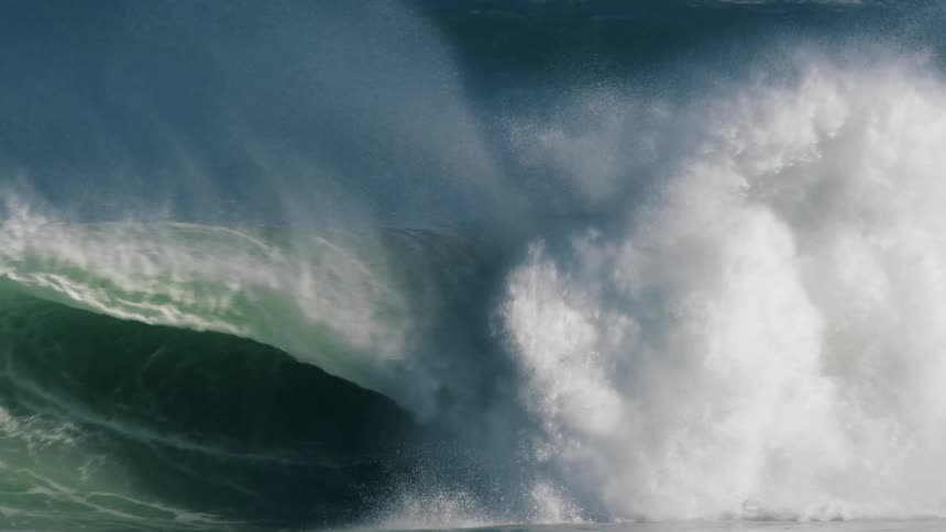 A man surfing in the ocean falls as a large wave washes over him