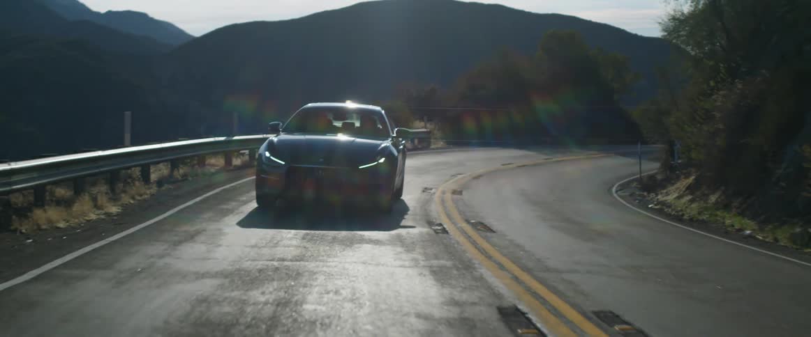 Sedan travels on the highway near the mountains on a sunny day