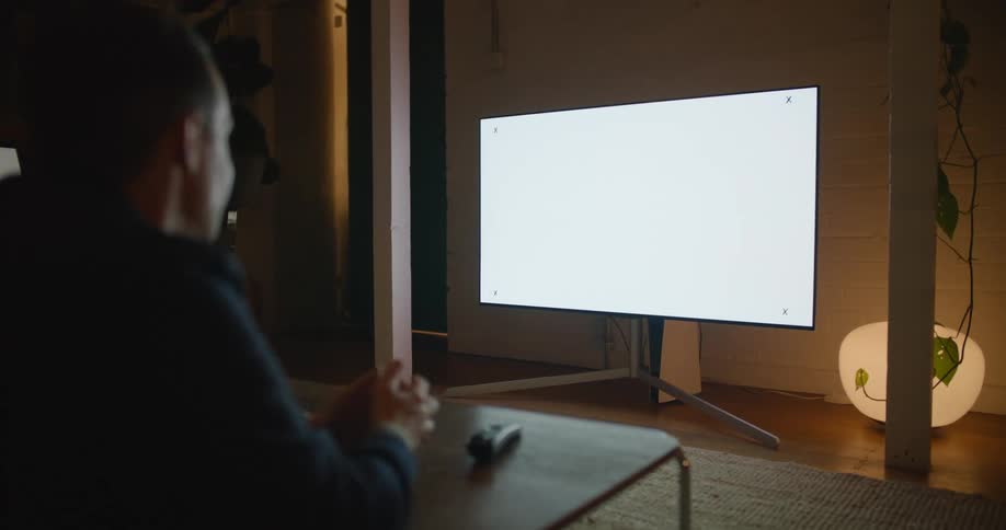 Man sits at a table and points to a large screen that has an x in each corner