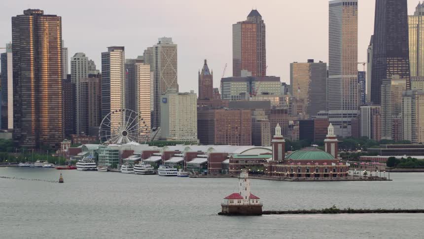A lighthouse sits in the lake across from a downtown city