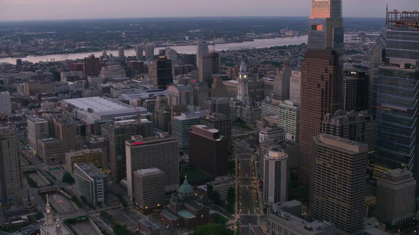Aerial view of city skyscrapers with buildings next to river at dusk