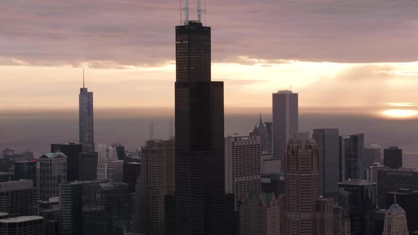 Aerial view of city skyscrapers and office buildings next to sea at sunrise
