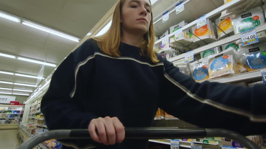 A woman putting a grocery item into her shopping cart while at the store