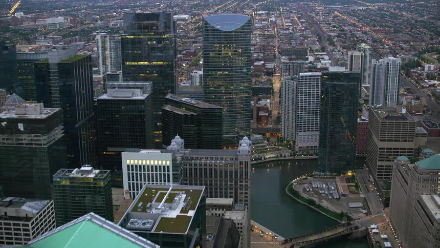 Aerial view of illuminated skyscrapers and office buildings next to the river in the city