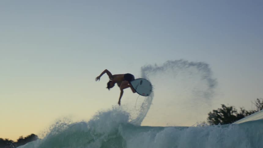 A surfer jumps a wave and crashes in the water