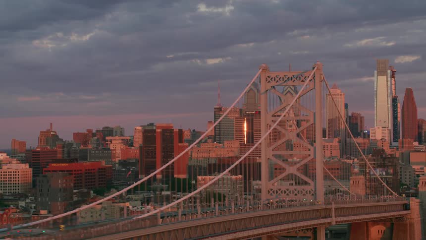 Bridge sits over the river in the city with skyscrapers nearby on a cloudy day