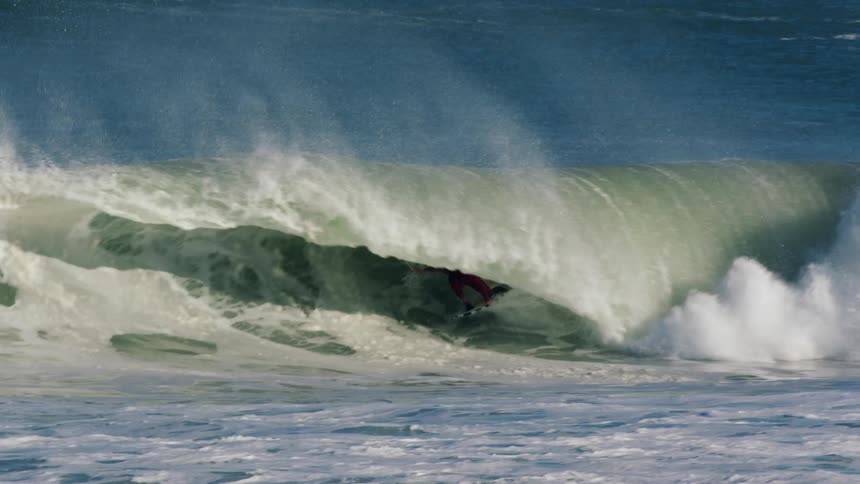 Surfer in wetsuit gets tubed surfing ocean wave