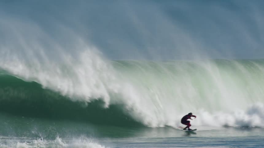 Person catches wave on surfboard and rides down until they fall into the water