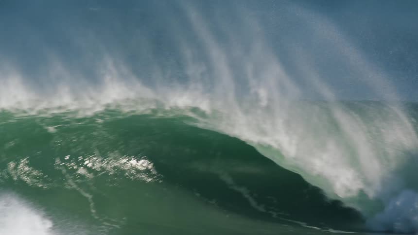 Sunlight shines on a wave that is splashing and foaming as it rolls in
