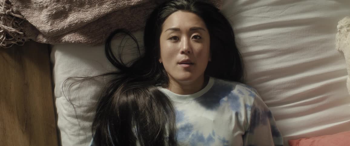 A woman lying down in bed and being disturbed by a glimmer of light in her face