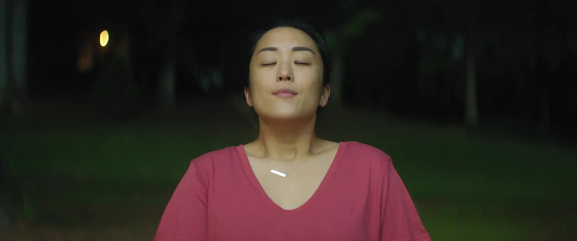A woman inhaling and closing her eyes while smiling outside