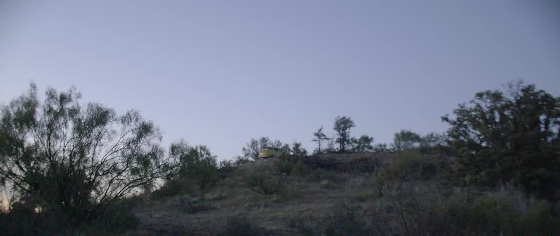 Lights shine bright out of a van on a hill