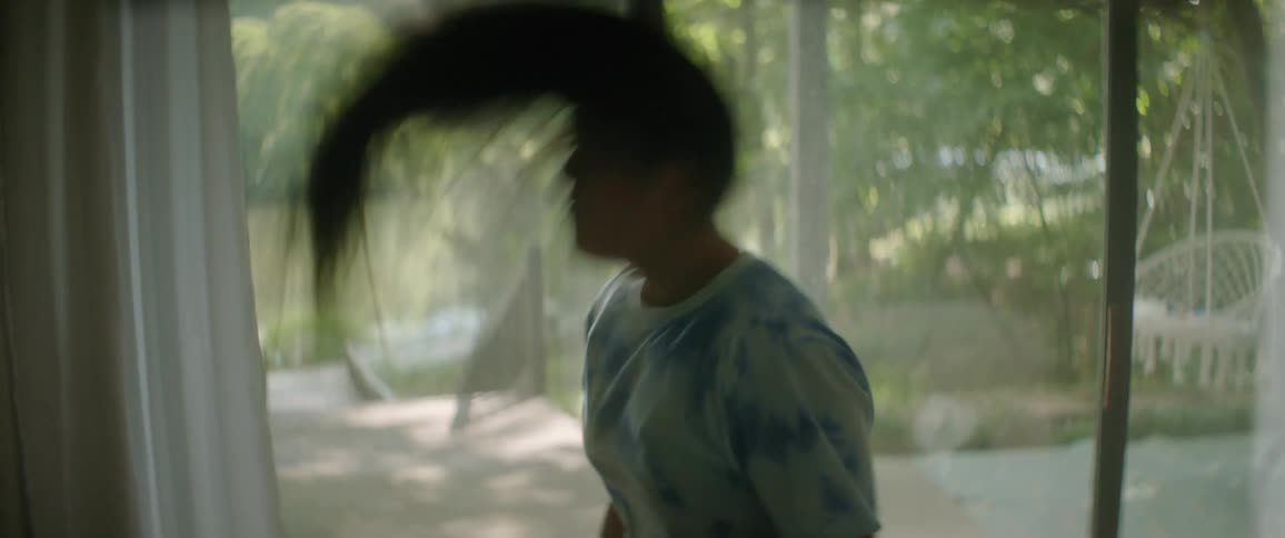 A woman is getting ready in her room in front of a window that shows lakefront property