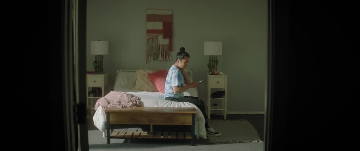 Woman sits on bed holding smartphone