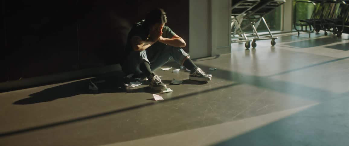 A person is sitting near the lockers crying into her hands seeing notes of rejection