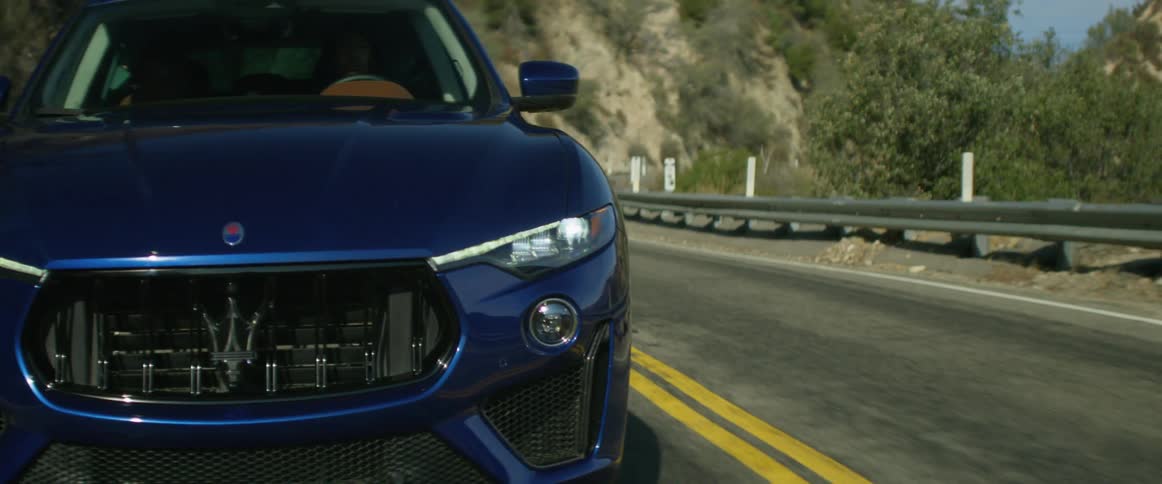 Blue sports car drives on mountain road
