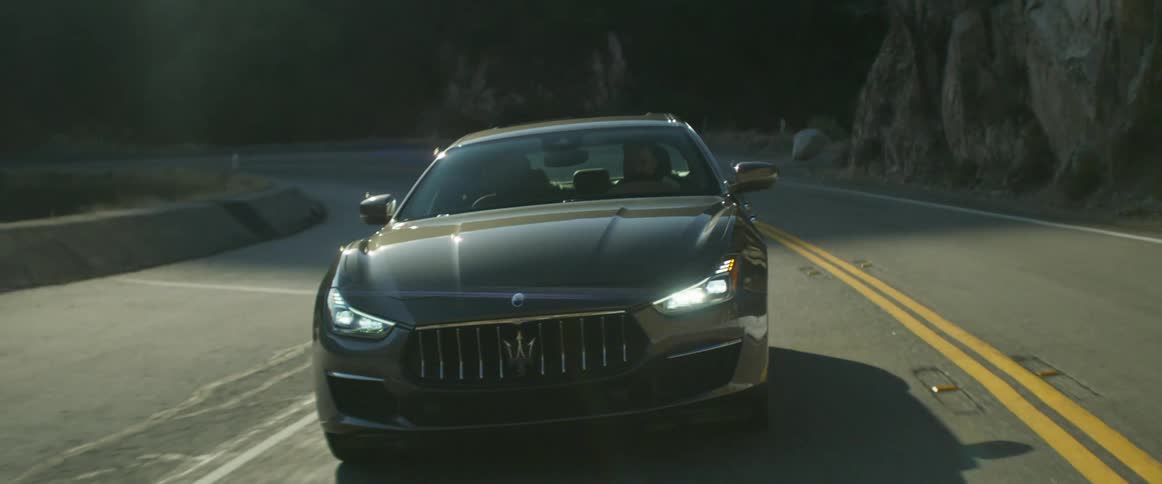 A car is driving along a mountain road next to cliffs
