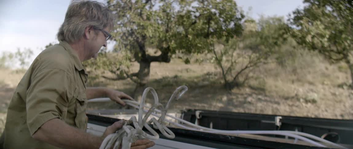A man is taking neon tubing out of a pickup truck bed