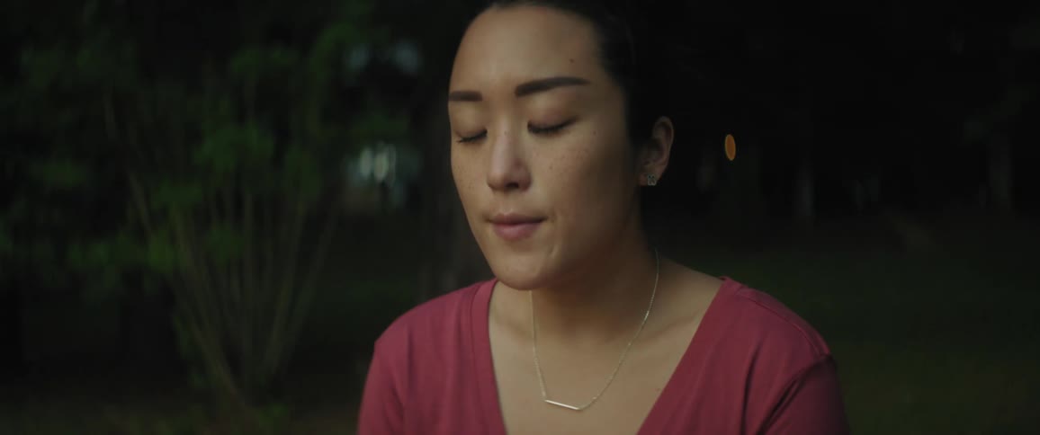 A woman is sitting outside praying and looking at the sunrise