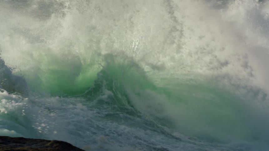 Rough water waves are splashing and foaming as they crash into rocks and roll into shore