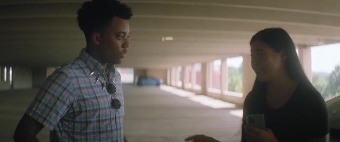 Two friends talk and laugh about something on her phone in the parking garage