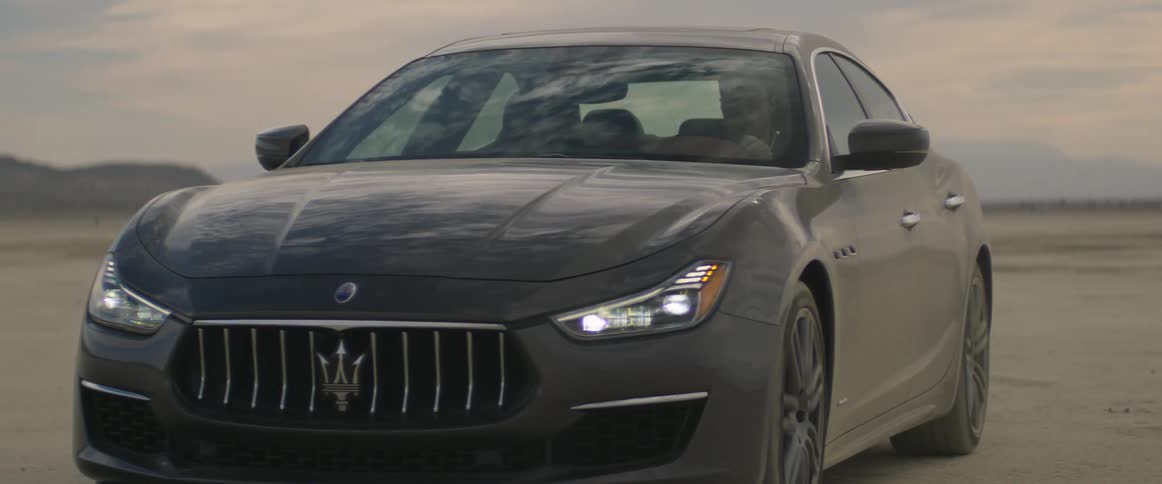 A sports car being driven in a desert in the daytime