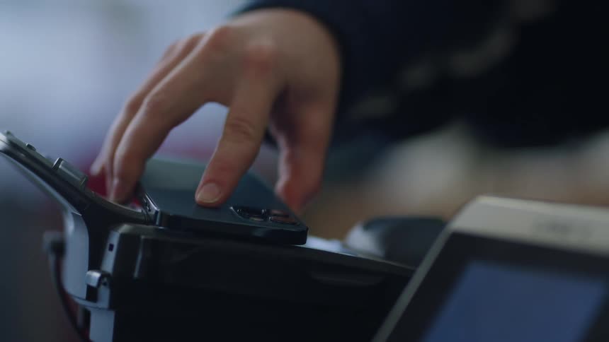 Woman pays using smartphone at checkout