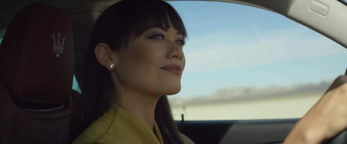 A woman smiles to herself while driving