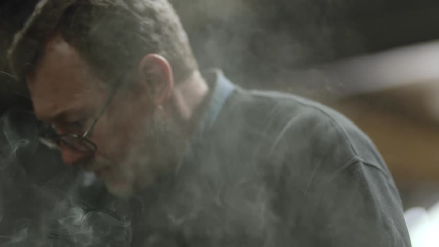 Heavy smoke rises around a mans face