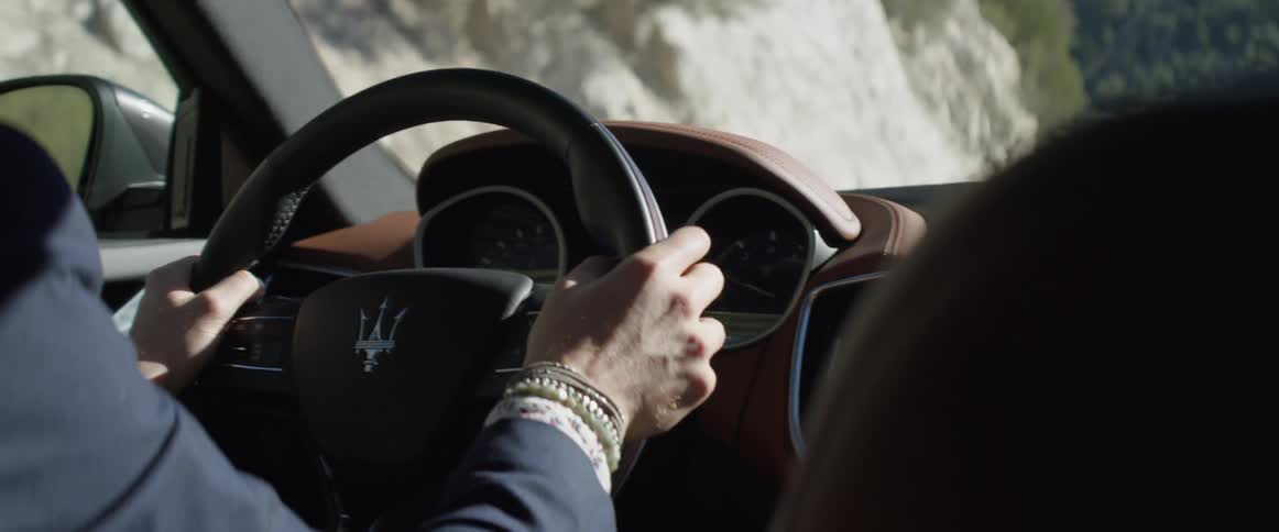 A man in a suit driving a car in the daytime