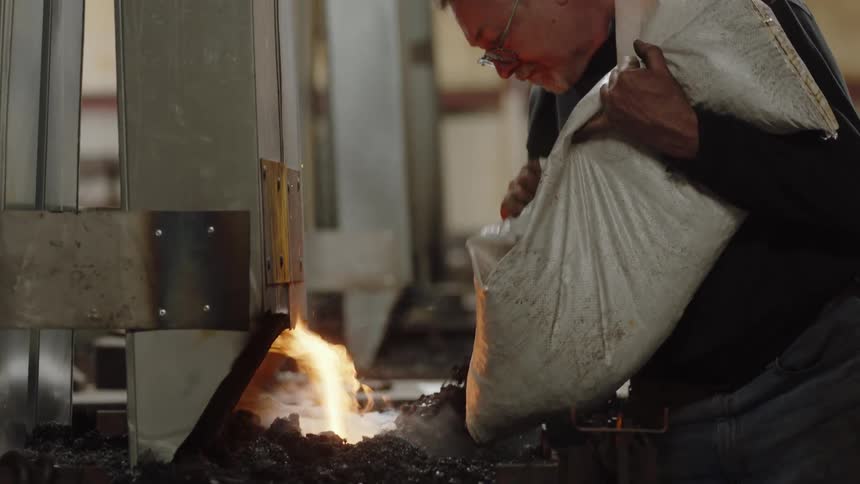 A man is putting more embers in a fire